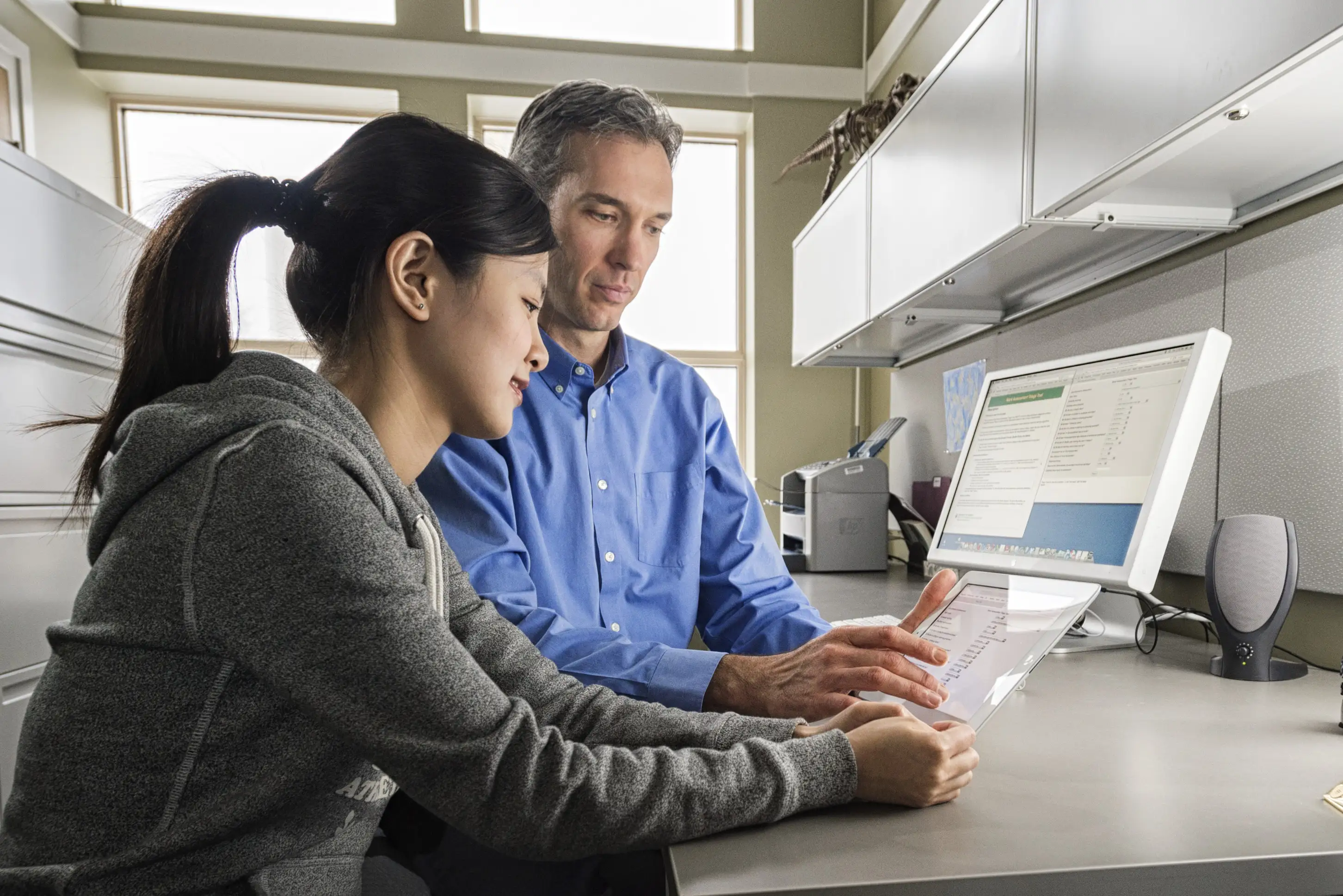 Student and professor holding and looking at tablet