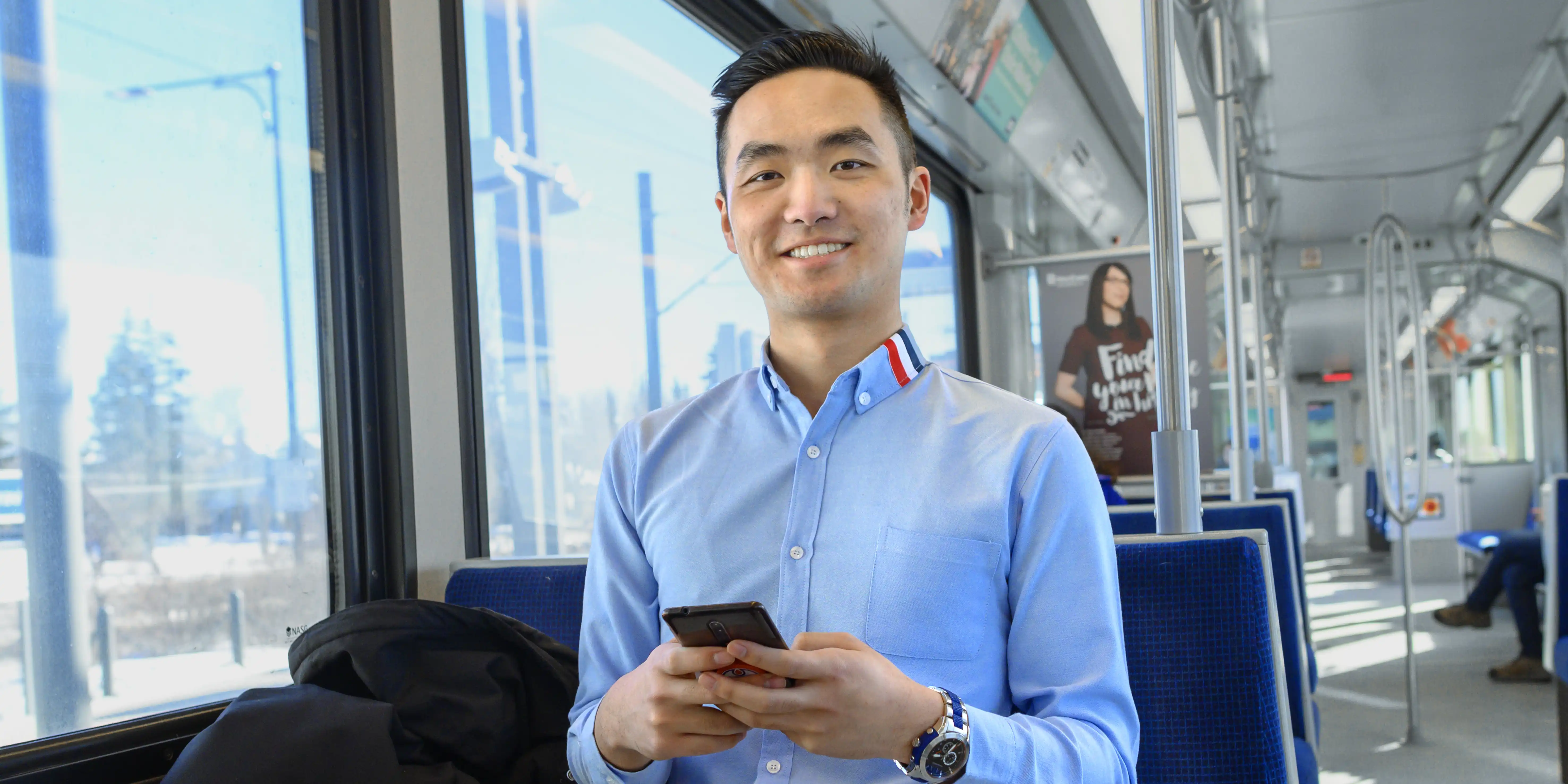 student holding phone on public transit bus