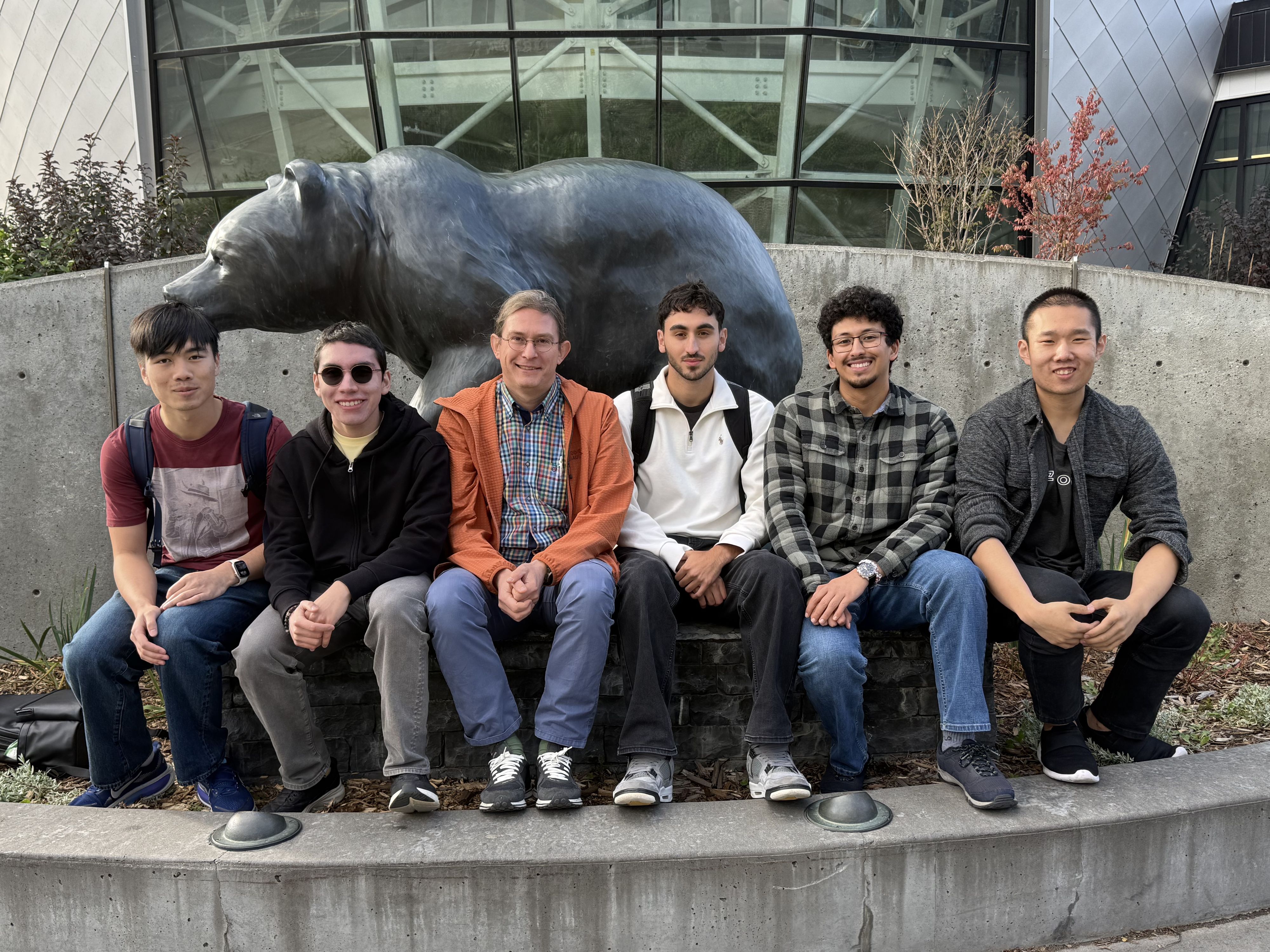 The lab team seated in front of the bear sculpture