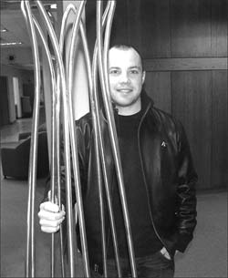 Recent industrial design graduate Brett Carlyle shows off his contribution to President Indira Samarasekera's office, a coat rack inspired by the lotus flower.